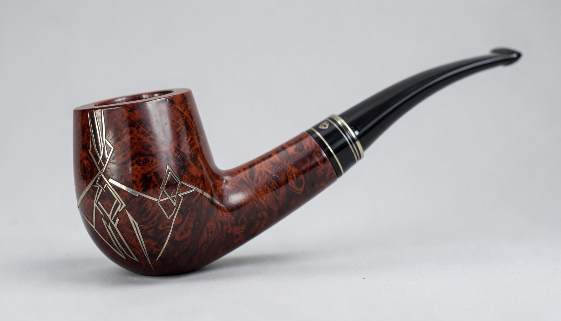 Elegant smooth-finished briar pipe with a slender bent stem, photographed on a neutral backdrop